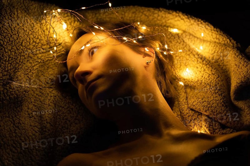 A woman in a dark room in the light of many string lights