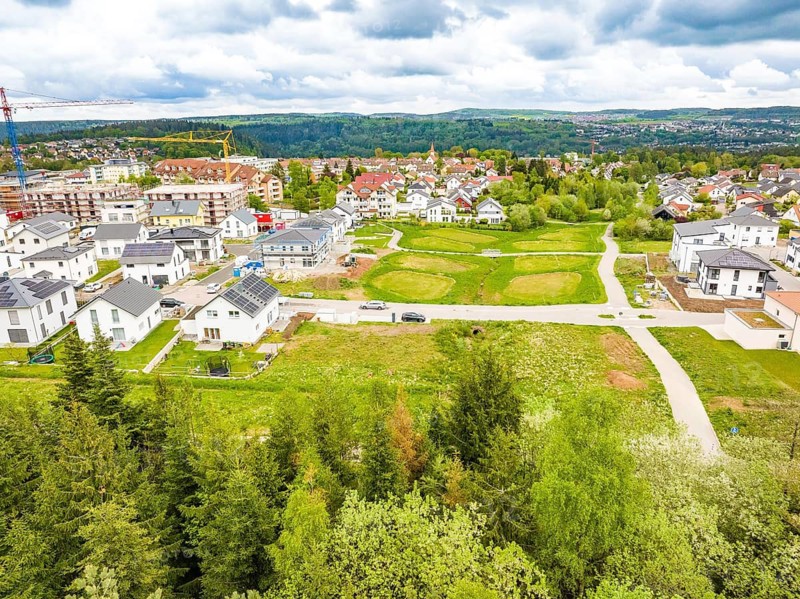 Aerial view of a residential area with lots of greenery and adjacent buildings, Deer charging stations, Calw, Germany