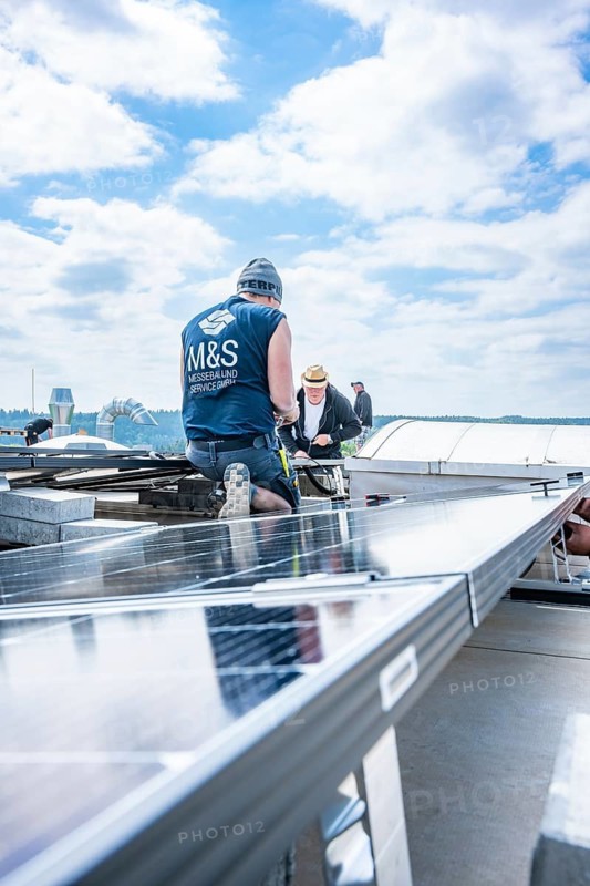 Two workers install solar panels under a cloudy sky, PV Montage, Perrot company, Calw, Germany