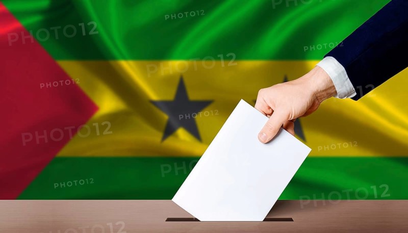 Sao Tome and Principe Presidential vote. Hand placing a ballot in ballot box with the Sao Tomean flag in the background