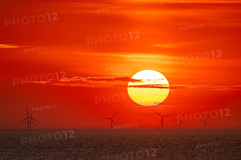 Dramatic sunset over the sea, wind turbines and wind turbines on the horizon, streaks of clouds, Houvig Beach, North Sea, Denmark