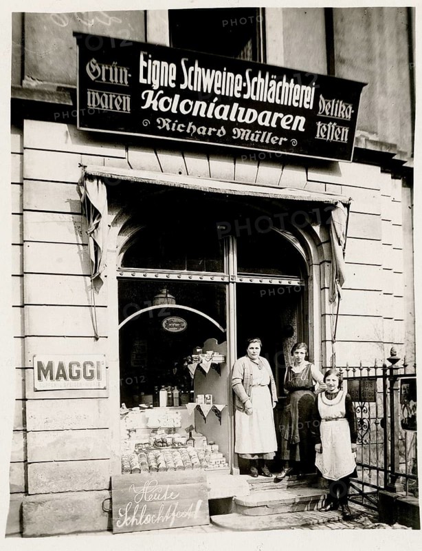 Colonial goods, pig slaughterhouse, butcher, food, shop, profession, twenties, Richard Müller, woman standing in front of a combination of butcher and colonial goods shop, seeing signs and goods around 1920