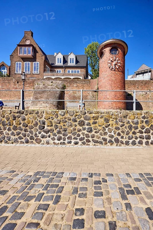 Rhine level Rees, level tower, level clock, quarry stone wall, general architecture, houses, waterfront, metal railings, concrete paving stones, cobblestones, tree, blue sky, cloudless, Rhine promenade, Rees, Kleve district, North Rhine-Westphalia, Germany