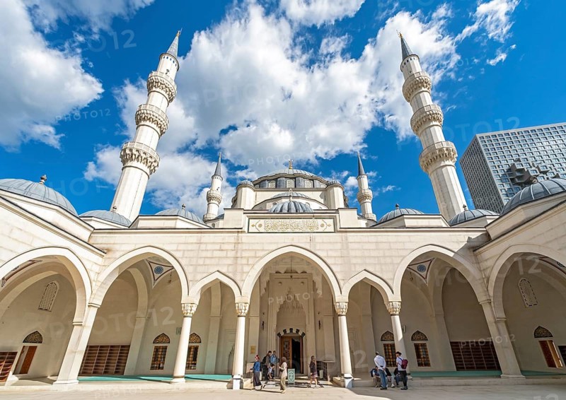 A wide-angle view of the courtyard, arches, and towering minarets of the Namazgah Mosque under a blue sky, Tirana, Albania