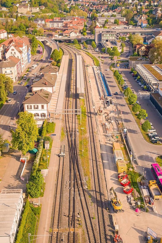 Bahnhofstraße with tracks and construction, surrounded by buildings and green trees in sunny weather, electrification of the Hochrheinbahn, conversion of the station, Waldshut, Tiengen, Germany