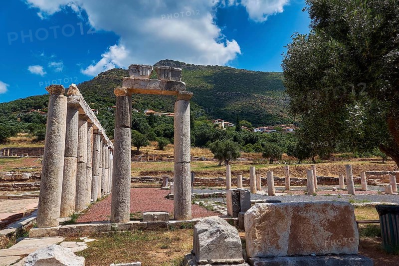 Ancient columns with stone formations against green hill and blue sky, ancient site, archaeological site, Messene, Messini, Messinia, southwest of the Peloponnese, odyssey, Odyssey, Odysseus, Ulysses, film, filming location, Matt Damon, Peloponnese, peninsula, Greece