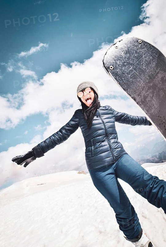 Happy excited cool caucasian brunette woman with skies pose in winter outfit in mountains. Copy paste vertical background top left.Gudauri.Georgia