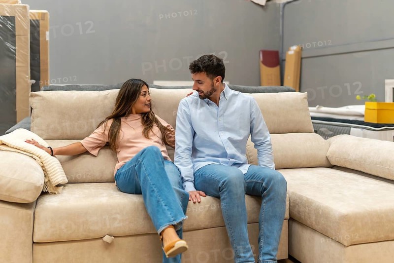 Couple is sitting on a comfortable sofa in a furniture showroom, discussing design ideas while shopping for new items to furnish their living space and improve their home