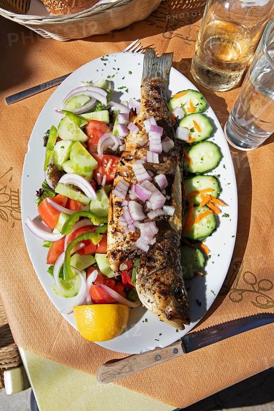 Grilled sea bream or bream mackerel or pomfret or goldhead on fresh Greek salad, Crete, Greece