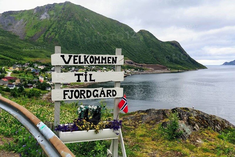 Town entrance sign to the small fishing village of Fjordgård, inscription Welcome, coastline on the fjord, Fjordgard, Troms, Norway