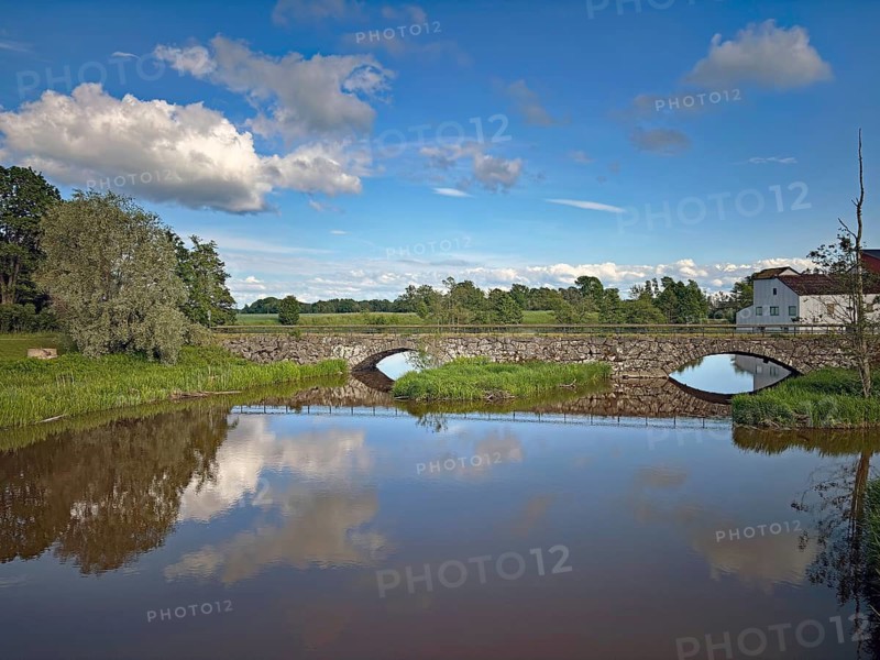 Stone bridge with two arches across a river surrounded by fields under blue sky, Haverud, Dalsland, Sweden