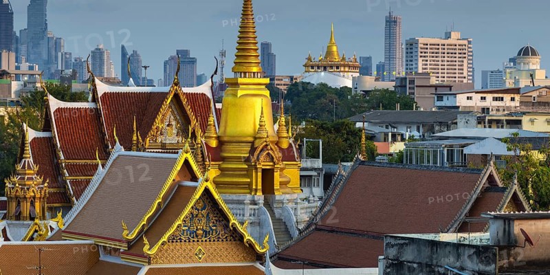 Wat Tri Thotsathep Worawihan with the Chedi glowing in the evening sun, Golden Mount behind it and the skyline of Bangkok, Thailand