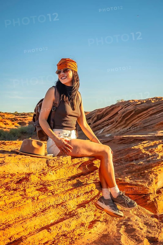 Young woman sitting on sandstone rock capturing the beauty of the arizona desert landscape, enjoying a moment of travel and adventure during her journey through nature