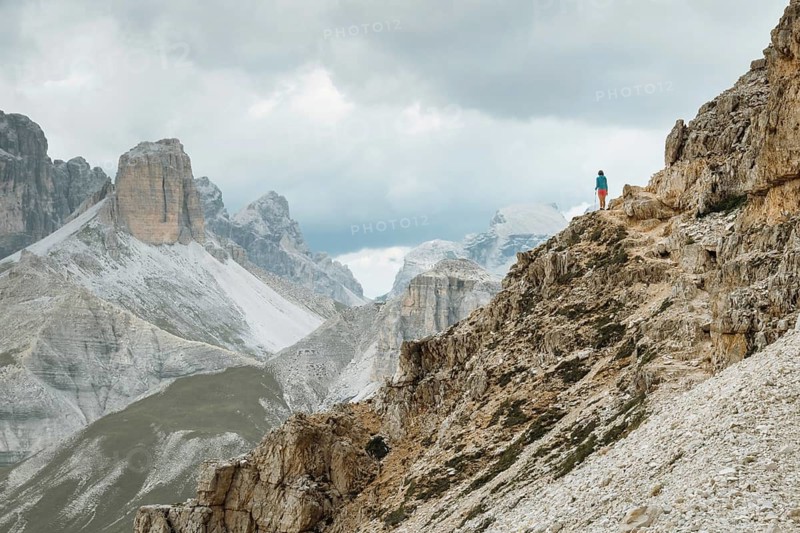 Lone Hiker on trek Standing on High Rocky Mountain Ridge Tre Cime Dolomites Italy