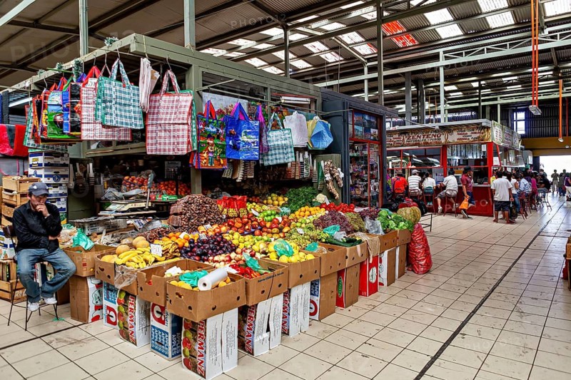 Lively covered market with colorful fruit display and shopping bags, bustling atmosphere, The Calama market hall in Chile