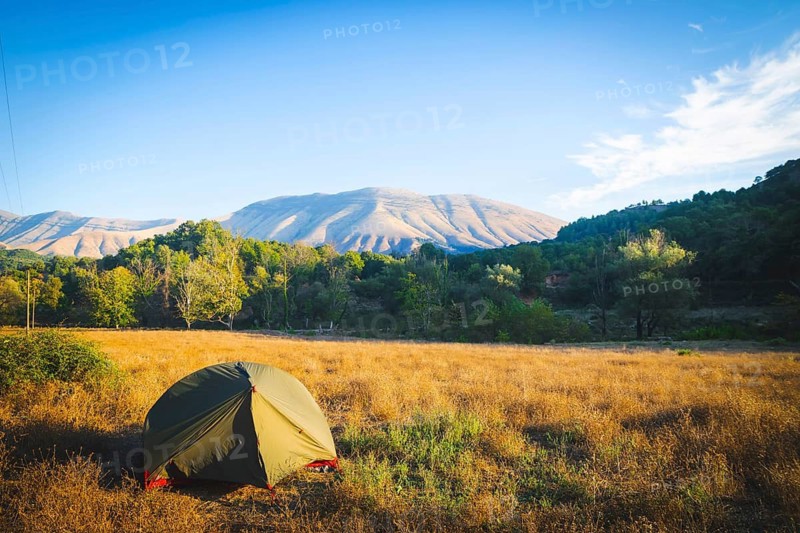 Gren tent standing suorunded by green pristine nature in Albania countryside. Wild camping in Balkans. Albania