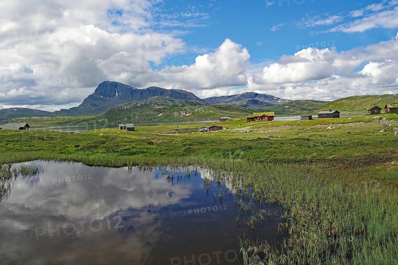Lakeside mountain hut with clear reflections of mountains and clouds in water, Bygdin, Jotunheimvegen, Mjolkevegen, Valdesflye, Norway