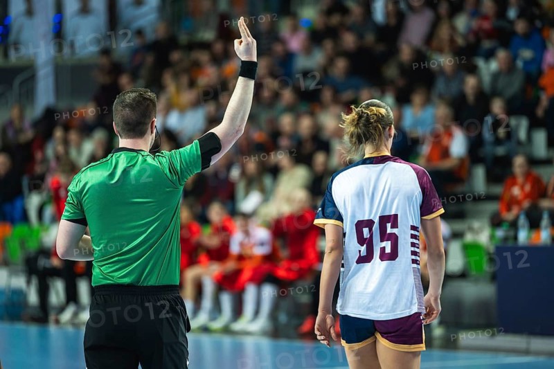 A handball referee showing a two-minute suspension sign with fingers during a high-stakes professional sports game in Lubin, Poland