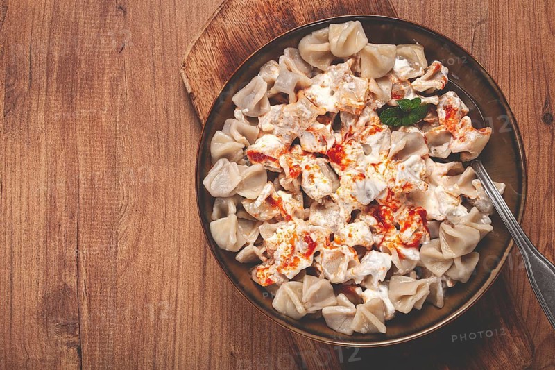 The dish features a generous serving of Turkish dumplings topped with velvety yogurt and a drizzle of spicy red sauce