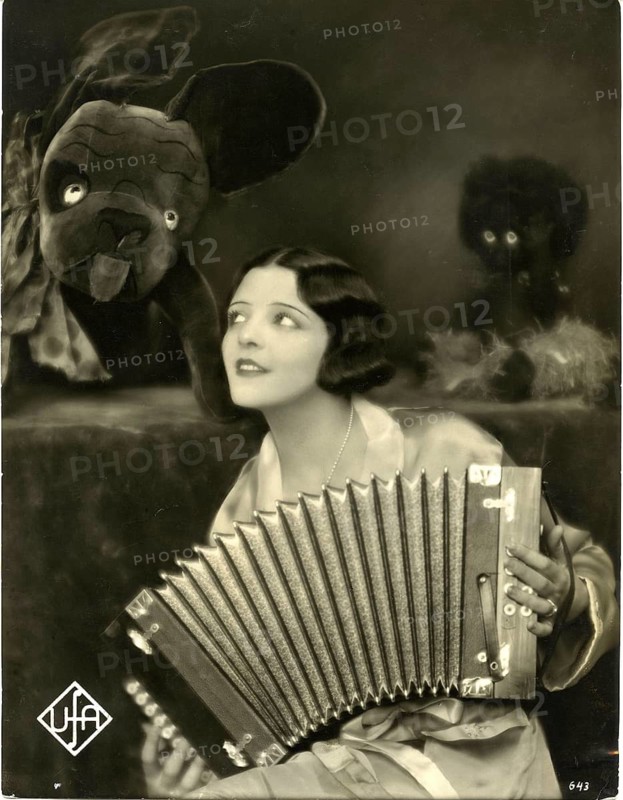 Trude Berliner actress, film, UFA, variety show, operetta, 1904-1077, Jewish, escape, emigration, Hollywood, A woman with an accordion and surrounded by puppets gives the picture a nostalgic touch, around 1930