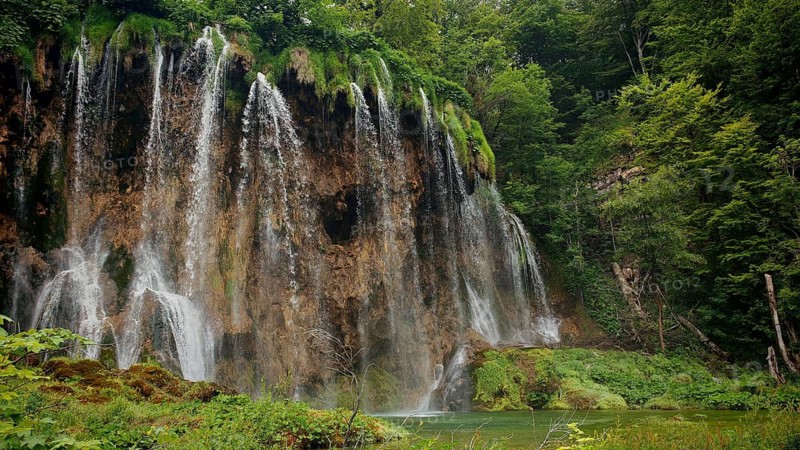 Majestic waterfalls flowing over mossy stones and rocks, Plitvice Lakes National Park, Croatia