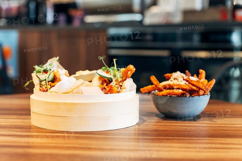 Bamboo Steamer with Soft Bao Buns and Sweet Potato Fries in a Restaurant Setting