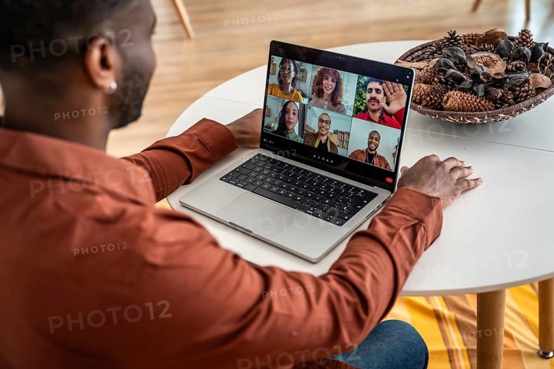 Black man participates in virtual support group on laptop, joining diverse people via video call for teletherapy, mental health support and remote counseling from home office