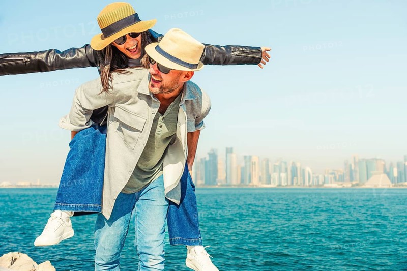 Multiracial beautiful young happy couple of lovers travelers - Multiethnic tourists travelling in middle east and visiting gulf country of Qatar. Doha corniche.Concepts tourism, couple travel lifestyle