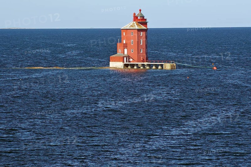 A red lighthouse stands isolated in the blue sea in calm weather, Kjeungskjær fyr, Trøndelag. norway