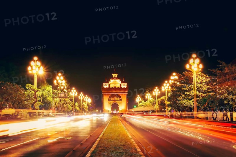 Vientiane, Laos - 15th february, 2025: Lane Xang Avenue and Patuxai Monument in Vientiane. Bright light trails and ornate street lamps glow along the capital main famous boulevard banner background