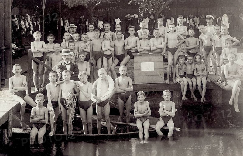 Swimming club, swimmer, outdoor pool, bathing, swimwear, men, children, leisure, fun, summer, young boys in swimming trunks standing next to a teacher at the water, around 1920