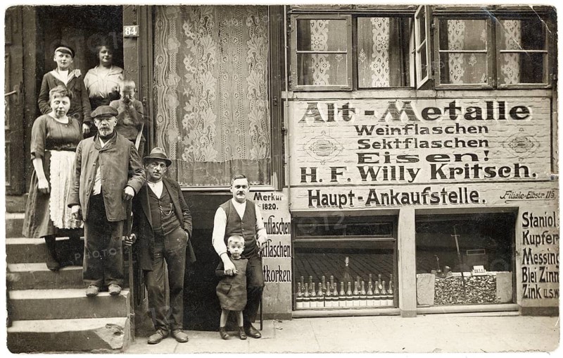 Scrap metal, iron, metals, bottles dealer, shop, shop, profession, twenties, poverty, cellar shop, men, woman and a child stand in front of a scrap metal shop, surrounded by advertising signs, around 1918