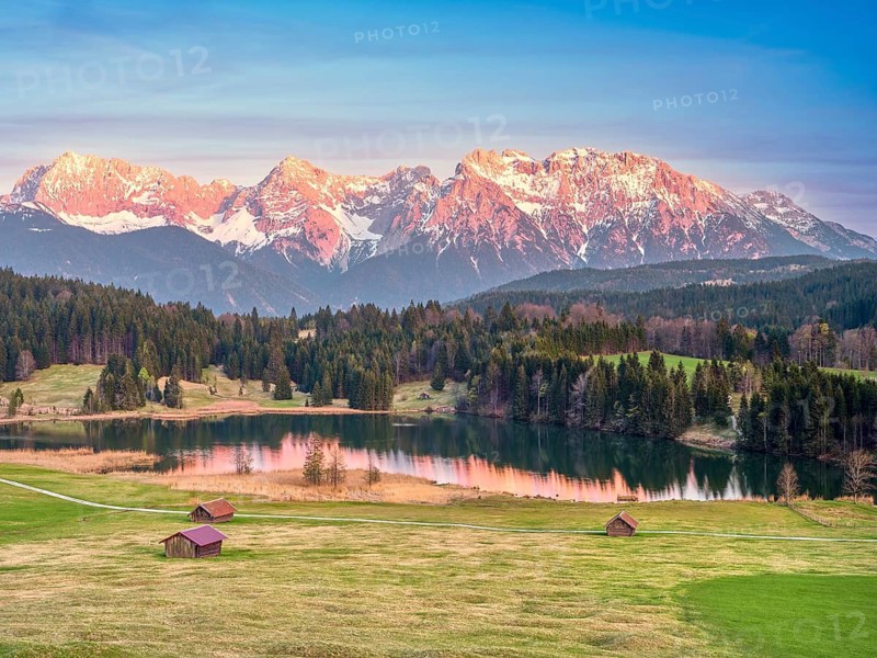 Mountains in Alpenglühen at sunset, quiet lake, green meadows with scattered huts, Karwendel Mountains, Geroldsee, Krün, Upper Bavaria, Bavaria, Germany