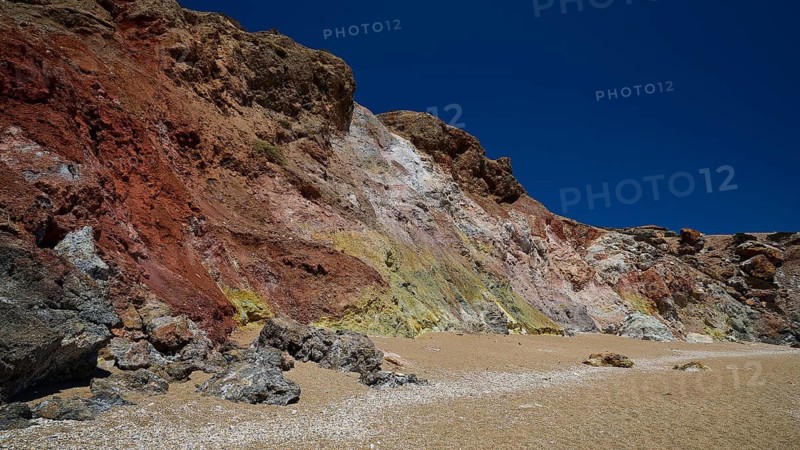 Colored rocks rise against a clear blue sky on a beach, Paliochori beach, Paliochori, volcanic rock, copper, nickel, mineral salts, volcanic island, Milos, Cyclades, Greek islands, Greece