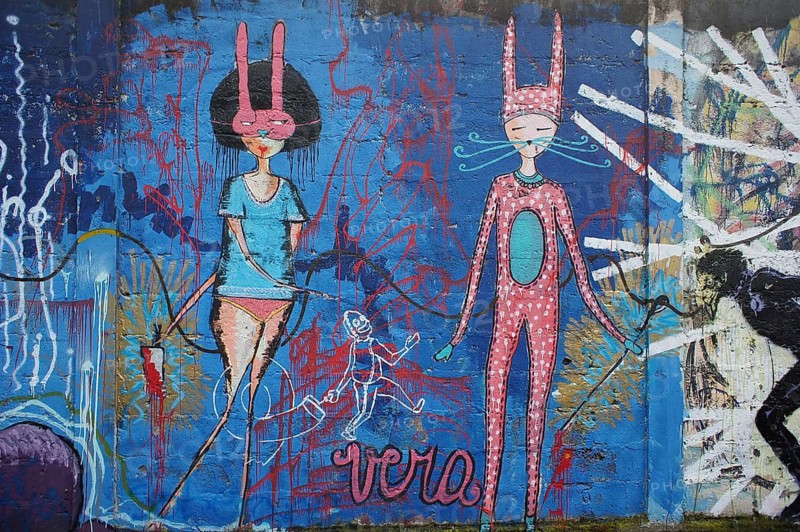 Abstract graffiti on a blue wall with figures in whimsical bunny costumes, Ecuador