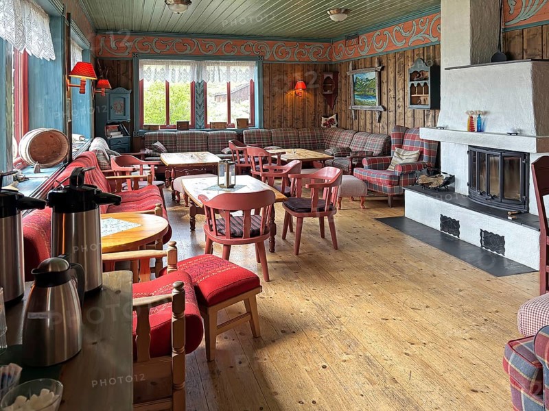 Cozy Scandinavian living room with wooden walls, red and white decor and a fireplace, Haugseter Fjellstue, tourist accommodation, bicycle route, Jotunheimveien, Mjolkevegen, Norway