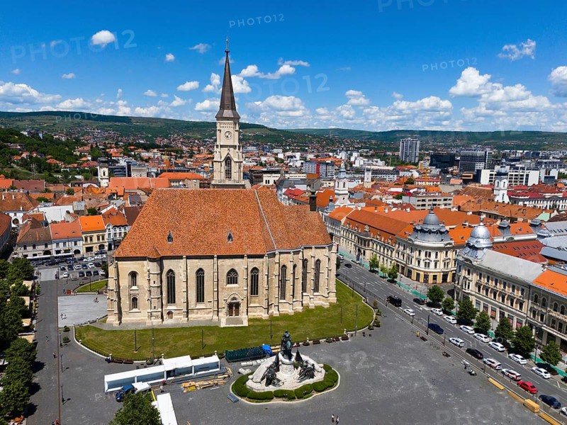 Historic church with red roof surrounded by city buildings under blue sky, aerial view, St. Michael's Church in Cluj, Gothic hall church, statue of Matthias Corvinus, Cluj-Napoca, Cluj, Transylvania, Romania