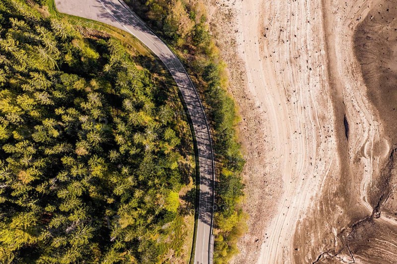Aerial view of a winding road on the edge of a wooded area and dry areas, emptied Schwarzenbach dam, Forbach, Black Forest, Germany