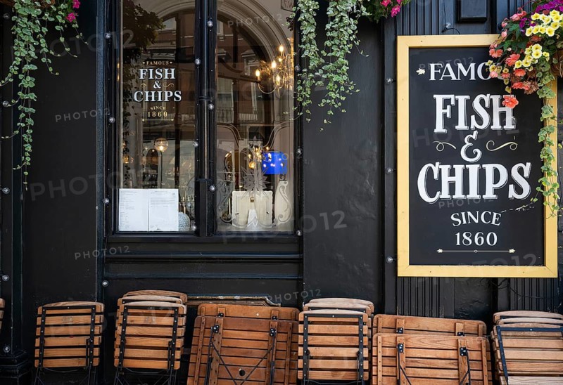 Wooden folding chairs lean against the exterior of a black-painted restaurant, traditional fish & chips restaurant, Royal Borough of Kensington and Chelsea, London, Great Britain, England, Great Britain
