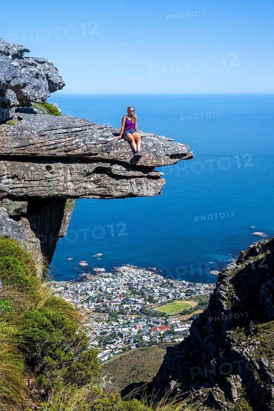 Young woman sitting on an imposing rock pin on a cliff, view of sea and coast, Kasteelspoort hiking, Table Mountains, Eastern Cape, Cape Town, South Africa