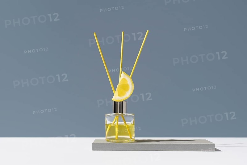 Elegant glass diffuser with lemon slice and floral motif. Yellow reeds release a refreshing citrus scent, perfect for home or office decor. Minimalist, modern design