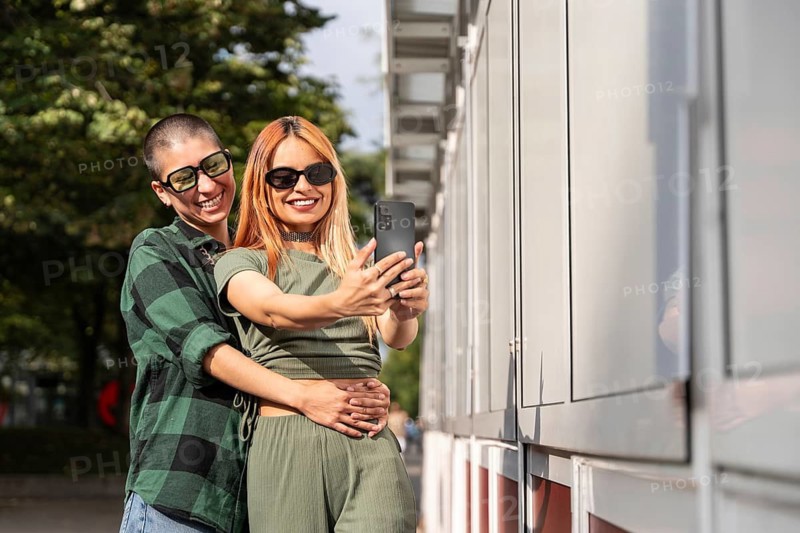 A Colombian lesbian couple joyfully takes a selfie outdoors. Their embrace reflects love, diversity, and pride in their identity. A positive representation of LGBTQIA+ unity