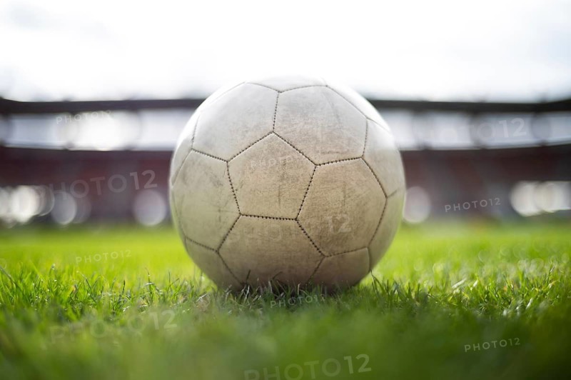 White soccer ball lying on the grass at stadium in Lubin, Poland