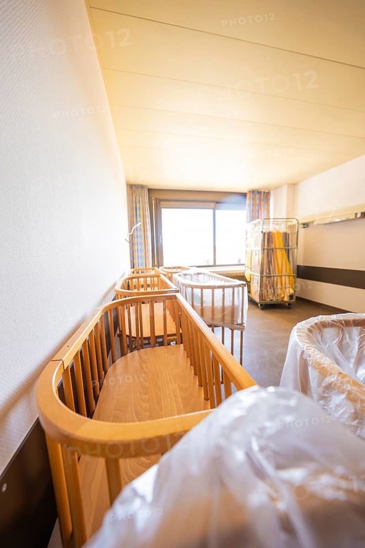 A room with several wooden cribs illuminated by daylight through a window, Obstetrics, Nagold, Germany