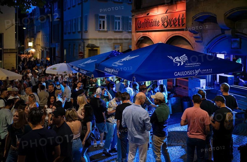 Night shot, district festival, bean quarter, bean quarter festival, people celebrating in front of restaurant board, parasol with advertising, advertising for Gauloises, Stuttgart, Baden-Württemberg, Germany
