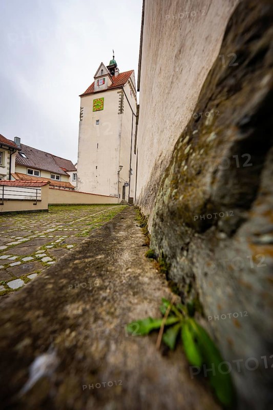 Next to a stone wall with a view of an old tower on an overcast day, Isny, Allgäu, Bavaria, Germany