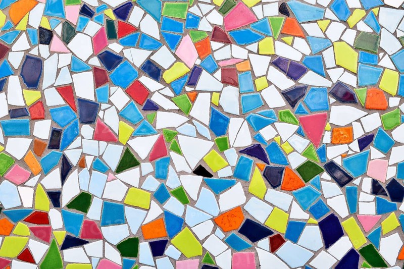 Close up of wall made of irregular small colorful mosaic stones, uneven textured decorative surface with vibrant pattern