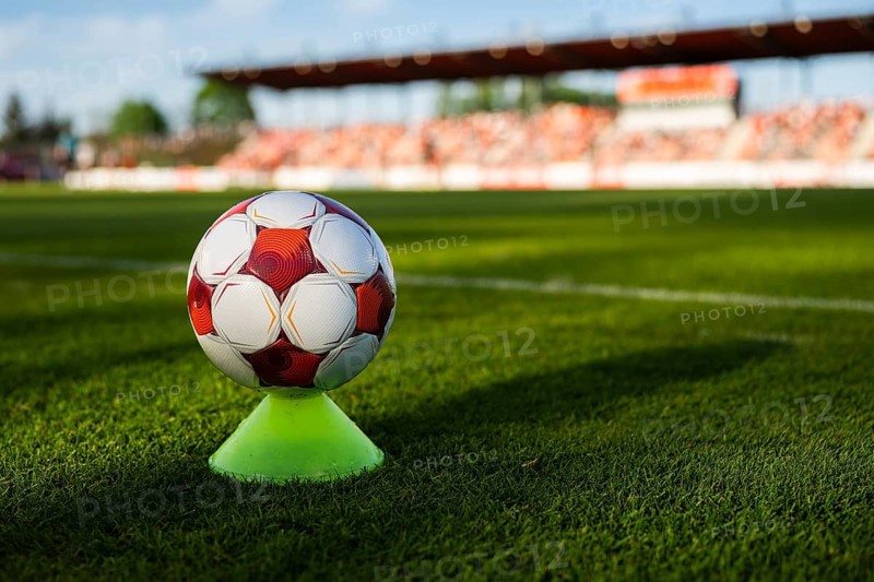 Soccer ball balanced on a training cone on a football pitch with stadium stands blurred in the background in Glogow, Poland