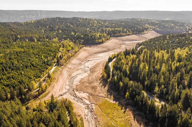 Aerial view of a dry riverbed surrounded by autumnal forests, emptied Schwarzenbach dam, Forbach, Black Forest, Germany