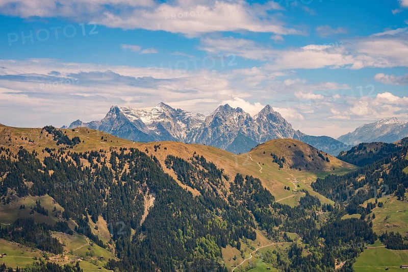 Expansive view of Alps and valleys under clear skies with lush forests, Hahnenkamm, Kitzbühel, Austria